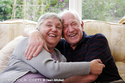 eiderly couple hugg and laugh on the sofa at home